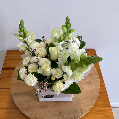Bouquet of white flowers on a wooden board against a light gray wall