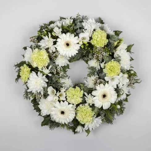 This white flower cluster wreath features classic flowers in white, pale green, and mid green tones, including a range of carnations, gerberas and chrysanthemums amongst ivy berry and gum. This beautiful floral tribute is ideal to help you pay your respects. Order online today. 