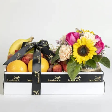 Gift Hamper with Seasonal Fruit & Fresh Flowers  Express your thoughts with an exquisitely presented fruit and flower hamper. A lovely assortment of fresh seasonal fruit and a floral arrangement featuring sunflowers, roses and carnations. Presented in a large box with ribbon, this gift is perfect for a new mum, or to spread best wishes or condolences.